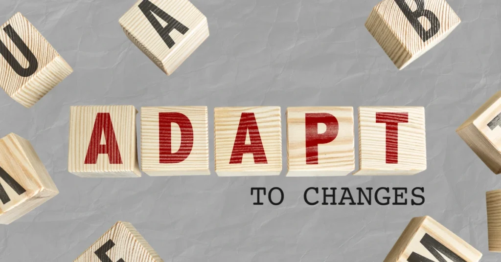 Wooden letter blocks spelling “ADAPT to CHANGES” on a textured grey background, symbolizing flexibility and change.