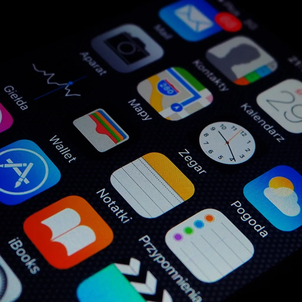 Close-up of an iPhone screen displaying various colorful app icons in Polish language.