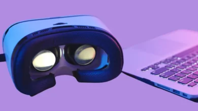 Close-up of a virtual reality headset next to a laptop keyboard on a purple background, showcasing modern tech gadgets.
