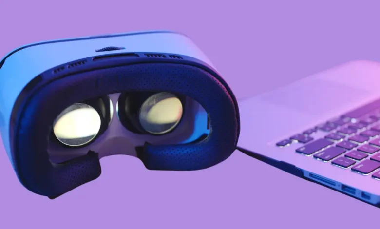 Close-up of a virtual reality headset next to a laptop keyboard on a purple background, showcasing modern tech gadgets.